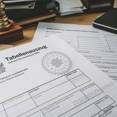 Tabellenauszug mit gedrucktem Siegel, Fallnummer und Forderung, neben Pfändungsbeschluss und Kugelschreiber.